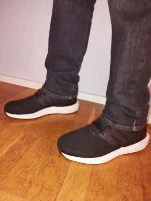 Svarta Adidas sneakers med vit sula - Svarta Adidas sneakers med klassiska tre ränder på sidan och vit, tjock sula. Ovandelen är i mesh-tyg för bra andningsförmåga och skorna har svarta skosnören. Perfekta för en sportig och avslappnad stil. Priset kan diskuteras vid snabb affär 