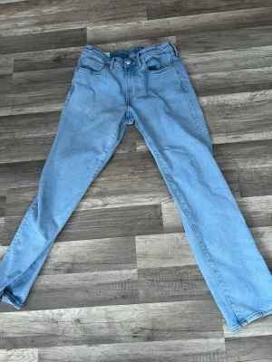 Ljusblå raka jeans från HM - Säljer ett par ljusblå jeans med rak passform och klassisk femficksdesign. Jeansen har normal midja och är tillverkade i denim med en mjuk känsla. Perfekta för en avslappnad och trendig look.