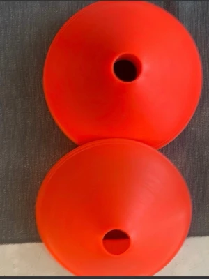 Röda markeringskoner för träning med tex hund - Tio röda markeringskoner i plast, perfekta för träning, sport eller lekar med tex hund.  Konerna är runda och har ett hål i toppen, vilket gör dem enkla att stapla och förvara. Passar bra för att markera ytor eller banor på både gräs och inomhus.