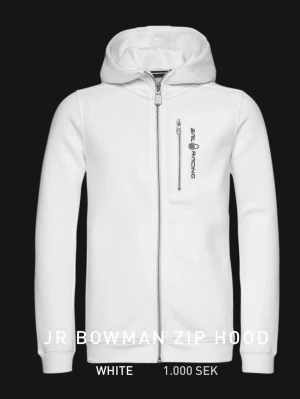 Vit zip hoodie från Sail Racing - JR BOWMAN ZIP HOOD. Snygg vit hoodie från Sail Racing med dragkedja framtill och en bröstficka med zip och logga. Endast använd fåtal gånger. Orginalpris 1000kr, Storlek: 170