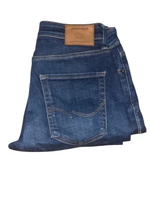 Blå jeans från Jack & Jones - Snygga blå jeans från Jack & Jones med klassisk femficksmodell och kontrastsömmar. Jeansen har en rak passform och är tillverkade i mjuk bomull med en skön stretch. Perfekta för dig som vill ha en tidlös och avslappnad look.