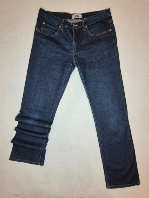Acne - Säljer ett par mörkblå jeans från Acne med klassisk femficksmodell och raka ben.             Mått(cirka): 75cm inre ben, 100cm yttre ben, 42cm midja, 22cm gren, 15cm gylf, 20cm benöppning. 