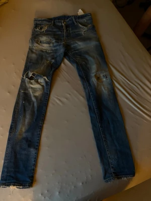 Mörkblå slitna skinny jeans - Snygga mörkblå skinny jeans med slitningar och hål på knäna. Jeansen har en tvättad look med ljusa partier och råa kanter vid bensluten. Perfekta för en trendig och avslappnad stil. Kan tyvärr inte visa hur dom sitter på eftersom dom är för små för mig 