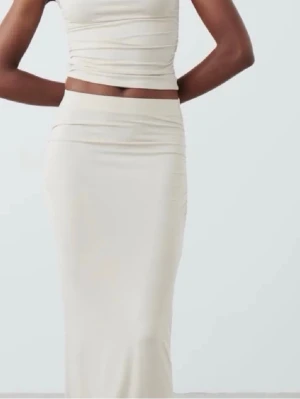 Lång beige kjol med hög midja - Säljer en stilren långkjol i beige med hög midja och figurnära passform. Kjolen har en slät yta och är tillverkad i ett mjukt material som ger en elegant siluett. Perfekt att matcha med crop tops eller stickade tröjor.