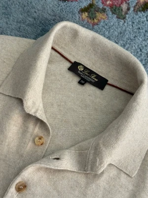 Loro Piana Baby Cashmere Arona Polo - Loro Piana Arona Polo i 100 % Baby Cashmere, en av världens mest exklusiva och sällsynta naturfibrer. Den finstickade 12-gauge-konstruktionen ger en otroligt mjuk känsla, låg vikt och en tidlös silhuett. Tillverkad i Italien med Loro Pianas välkända hantverk och kompromisslösa kvalitet. Nypris €1800
