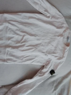 Vit sweatshirt från Stone Island - Säljer en stilren vit sweatshirt från Stone Island med klassisk rund halsringning och ribbade muddar. Tröjan har den ikoniska Stone Island-loggan på ärmen och är tillverkad i mjukt bomullsmaterial. Perfekt för en clean och avslappnad look.