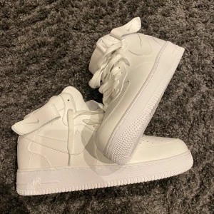Vita Nike Air Force sneakers - Säljer ett par klassiska vita Nike Air Force sneakers. Skorna har hög modell. Pris kan diskuteras. Helt oanvända 