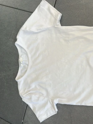 Klassisk vit t-shirt i bomull - En enkel och stilren vit t-shirt med rund hals och korta ärmar. Tillverkad i mjuk bomull som känns skön mot huden. Perfekt basplagg att matcha med allt i garderoben. Pris kan absolut diskuteras!