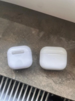 Apple AirPods gen3/4 - Säljer ett par vita trådlösa in-ear hörlurar med laddningsetui. Hörlurarna har en stilren och kompakt design med rundade kanter och laddningsindikator på framsidan av etuiet. Perfekta för musik, poddar och samtal på språng.