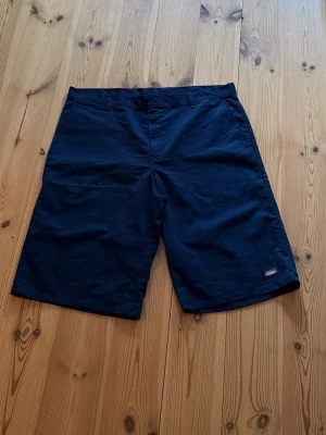 Mörkblåa loose shorts - Säljer ett par mörkblåa shorts i loose fit med klassisk design. Shortsen har bälteshällor, raka ben och diskreta fickor både fram och bak. Perfekta för sommardagar och enkla att matcha med olika stilar.