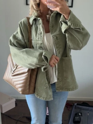 Oversized grön jeansjacka - Snygg oversized jeansjacka i ljusgrönt med stora fickor framtill och avslappnad passform. Jackan har klassisk krage och knäppning framtill, perfekt för en trendig och avslappnad look.