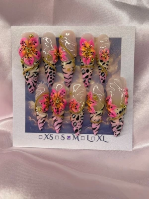 Frankie (M);ExtraLongStiletto  - Set unika handgjorda extralånga press-on naglar i stilettoform med leopardmönster i svart och rosa, dekorerade med 3D-blommor i neonrosa, gult och orange samt guldfärgade detaljer. Naglarna har en transparent bas och coola swirl-mönster. Perfekt för dig som vill sticka ut! Inspiration av Lisa Frank ✨💛M: 16 mm, 12 mm, 12,5 mm, 11,5 mm, 10 mm