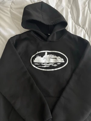 Svart Corteiz - Säljer en svart Corteiz hoodie med stor skön huva. Hoodien har klassisk passform och är gjord i mjukt material, perfekt för chill dagar. 