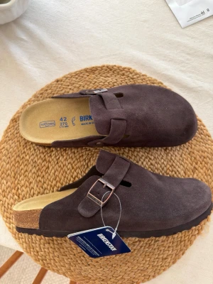 Bruna Birkenstock Boston tofflor - Säljer ett par klassiska Birkenstock Boston tofflor i mörkbrunt mocka. Säljes pga en storlek för små. 