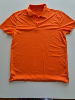 Orange piké t-shirt med krage(golf) - Snygg orange piké t-shirt med klassisk krage och knappar framtill. Perfekt för dig som vill sticka ut med färg! Tillverkad i mjukt material och har korta ärmar för en avslappnad look.