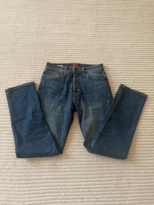 Jeans från Jack&Jones - Säljer mina jeans i relaxed passform från Jack&Jones som tyvärr inte kom till användning efter att ha fått dom. Orginalpris drygt 600kr. Storlek 29/32 så passar bra för den som har S i kläder. Sitter bra och passar fint i vardagen med nån skön hoodie till. Säljer för ett bra pris med tanke på perfekt skick! 