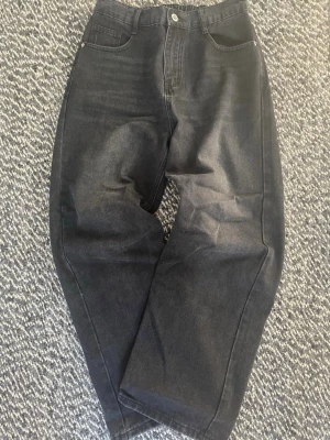 Svart grå baggy jeans y2k streetwear - Säljer ett par grå jeans med loose fit och raka ben. Jeansen har klassisk femficksdesign och hög midja. Materialet är denim och färgen är tvättad svart med lätt slitning. Perfekta för en avslappnad och trendig look.