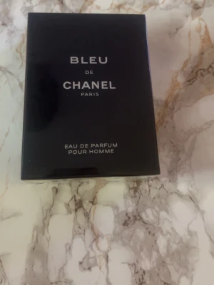 Bleu de Chanel Eau de Parfum - Bleu de Chanel Eau de Parfum Pour Homme från Chanel. Flaskan är mörkblå och elegant med stilren design. Förpackningen är rektangulär och tillverkad i kartong med silverfärgad text. En klassisk och maskulin doft från ett ikoniskt märke.