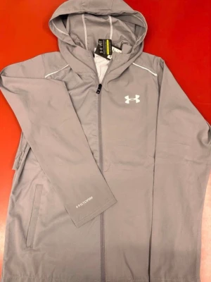 Under Armour Windbreaker Grå - Helt ny & Oanvänd ✔️, Storlek: M ✔️, Kommer med tags 🏷, Skickas inom 1 dag 🚀, Kontakta för mer info ☺️