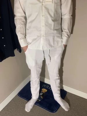 Vit skjorta från Tthese glory days - Klassisk vit skjorta från These glory days med knappar framtill och lång ärm. Skjortan har en clean och stilren look, perfekt för dig som gillar minimalistisk stil. Tillverkad i bomull för en skön känsla och bra passform. En sjukt snygg slim fit skjorta som matchar vädret just nu perfekt bara att skriva för mer bilder så fixar jag det. Killen på bilden är 179. Helt ny med prislapp