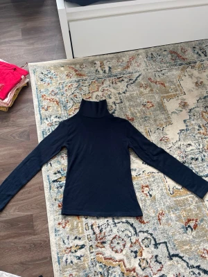 Svart stickade tröja med långa ärmar - Snygg svart stickade tröja med långa ärmar och tight passform. Perfekt att styla med jeans eller kjol. Stickade tröja ger en stilren look och tröjan är gjord i ett mjukt, stretchigt material som sitter skönt på kroppen.