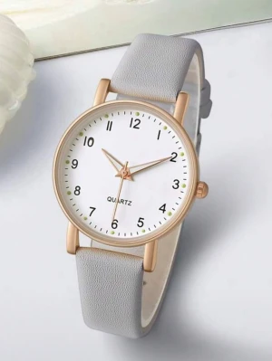 Stilren klocka med grått band - Snygg och minimalistisk klocka från Quartz med vitt urtavla, svarta siffror och guldfärgad boett. Klockan har ett mjukt grått band som ger en clean look. Perfekt accessoar för dig som gillar enkel och modern stil.