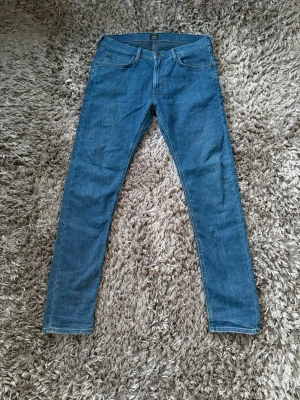 Blå slim fit jeans från lee - Säljer ett par klassiska blå slim fit jeans från Lee. Jeansen har fem fickor, normal midja och smala ben. Tillverkade i mjuk denim med lite stretch för extra komfort. Perfekta till en avslappnad stil.