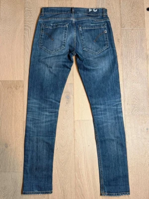 Dondup jeans - Snygga blå jeans från JC med smal passform och klassisk femficksdesign. Jeansen har diskreta slitningar och dragkedjedetaljer på bakfickorna. Perfekta för en avslappnad och trendig look.