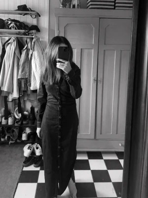 Lång jeansklänning med knappar - Snygg långärmad klänning i mörkblå denim med knappar hela vägen ner. Klänningen har en figurnära passform och klassisk skjortkrage. Perfekt för dig som gillar en stilren look.                                                             Endast använd 1 gång💞 Den har scrunch på båda sidorna