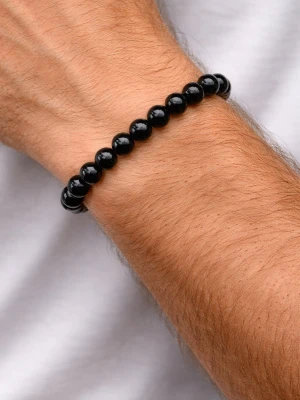 Svart Naturstenaarmband - Stilrent armband med svarta, blanka pärlor av obsidian. Pärlorna är runda och sitter på en elastisk tråd som gör det enkelt att ta på och av. Perfekt för dig som gillar minimalistiska accessoarer med en cool vibe.