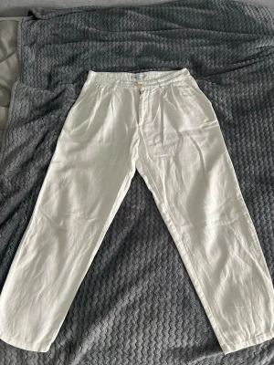 Vita linnebyxor från Zara - Snygga vita linnebyxor från Zara med rak passform och klassisk midja. Byxorna har knapp och dragkedja framtill samt sidfickor. Passar dig som brukar ha M i kläder och är runt 170-175 cm lång. Dem är bara använda max 5 gånger 