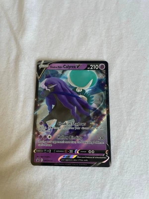Pokémonkort Shadow Rider Calyrex V - Säljer ett Pokémonkort, Shadow Rider Calyrex V, med holografisk yta. Kortet har lila, svart och blå färger och är från Sword & Shield-serien. Perfekt för samlare eller Pokémon-fans som vill utöka sin kortsamling.