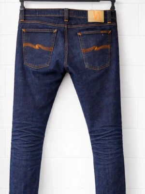 Mörkblå skinny jeans från Nudie - Säljer ett par mörkblå skinny jeans från Nudie med klassiska orange sömmar och broderade bakfickor. Jeansen har fem fickor. W32 L33/34