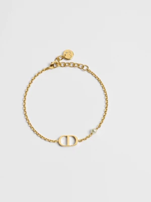 Guldfärgat armband med pärldetalj - Snyggt och stilrent armband från Dior i guldfärgad metall med tunn kedja, CD-logga och en liten vit pärldetalj. Justerbar längd med diskret Dior-mynt vid låset. Perfekt för dig som gillar minimalistiska smycken med exklusiv känsla. Armbandet är i bra skick. Jag har kvitto, box påse och äkthetsbevis. Nypris 4000kr. Perfekt att ge i present till någon!! Pärlan på armbandet är lite skadat och har tappat lite färg, men det är inget man tänker på.