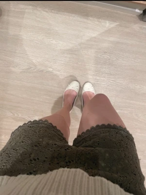 Olivgröna virkade shorts med spetskant - Säljer ett par olivgröna shorts med snygg virkad look och dekorativ spetskant. Shortsen har en midwaist passform och är perfekta för sommarens alla tillfällen. De är tillverkade i ett mjukt material som känns bekvämt mot huden.