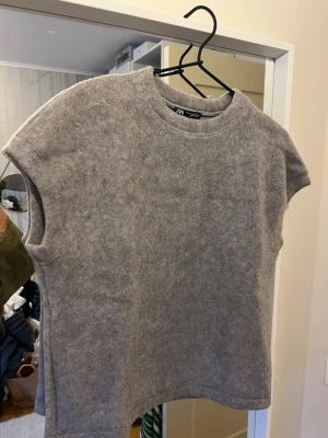 Grå ”stickad” topp från Zara - En enkel och stilren grå topp från Zara med rund halsringning och ärmlös design. Toppen har en mjuk och lite tjockare känsla. Aldrig använd så som ny! Passar xs-m💞🥰🙌🏽💓
