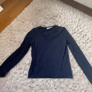 MARINBLÅ långärmad topp från Gina Tricot - Snygg marinblå långärmad topp från Gina Tricot med spetsdetaljer vid v-ringningen. Perfekt för en stilren look. Passar bra till både jeans och kjol. 🖤