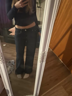 Mörkblå low waist bootcut jeans - Säljer ett par mörkblå low waist jeans med bootcut passform. Jeansen har klassisk femficksdesign och sitter lågt på höften för en trendig look. Perfekta för dig som gillar 00-talsstilen och vill ha ett par snygga, vida jeans.