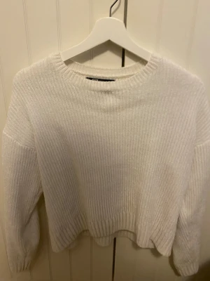 Vit ribbstickad tröja FB Sister - Mysig vit ribbstickad tröja från FB Sister med rund halsringning och långa ärmar. Tröjan har en mjuk struktur och avslappnad passform, perfekt för kyliga dagar. Enkel och stilren design som passar till det mesta.