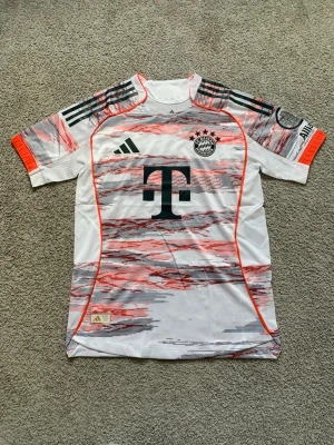 Bayern München Adidas matchtröja - Säljer en FC Bayern München matchtröja från Adidas i vitt med grå och röda grafiska detaljer. Tröjan har korta ärmar, klubbmärke och Adidas-logga på bröstet samt sponsortryck. Tillverkad i lätt och ventilerande material, perfekt för träning eller match. Priset kan sålklart diskuteras och kom gärna med frågor!