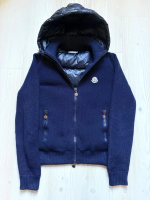 Moncler Cardigan - Extremt snygg och exklusiv cardigan jacka från Moncler. Modellen är ’’Moncler Maglione Tricot cardigan’’ detta är en extremt exklusiv och eftertraktad modell som inte längre tillverkas. Nypris på denna då var 14 000:-! Den är använd få gånger och få tecken på användning. Den är självklart 100% äkta, och Äktighetsbevis ser ni på sista bilderna. Det är inte heller någon av de kopiorna utan glans på ryggen samt med den där avslutande ’’QH’’ koden. Storlek L men sitter som en S/M. Marinblå färg. MVH