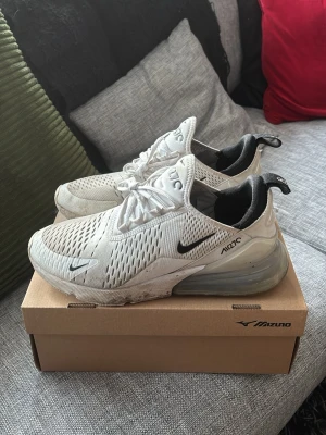 Nike Air Max 270 vita sneakers - Nike Air Max 270 sneakers i vitt med svarta detaljer. Ovandelen är i mesh för bra ventilation. Storlek 42 men jag skulle säga att de är 41.5. Använt ett fåtal gånger och har inge defekter förutom smuts lite här och där och någon lös tråd på baksidan.