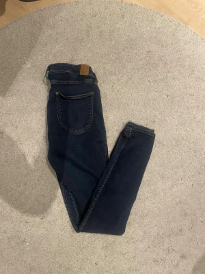 Mörkblå skinny jeans från Gina Tricot - Säljer ett par mörkblå skinny jeans från Grant, smal passform och normal midja. Perfekta till vardags och lätta att matcha med olika stilar. Materialet är mjukt och stretchigt för extra komfort.