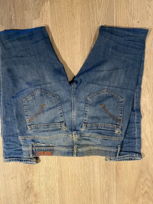 Blå raka jeans med kontrastsömmar - Snygga blå jeans med raka ben och klassisk femficksdesign. Jeansen har kontrastsömmar på bakfickorna och en liten detalj med siffran 30 vid linningen. Tillverkade i slitstarkt denim, perfekta för en avslappnad och trendig look. Som ni ser på bilderna är de några hål där bak men går enkelt att fixa