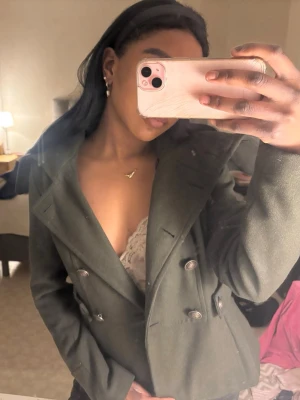 Mörkgrön dubbelknäppt kappa - Snygg mörkgrön kappa med dubbelknäppning och bred krage. Kappan har dekorativa knappar framtill och ett skräddat snitt som markerar midjan. Perfekt för dig som vill ha en stilren och trendig look. Pris kan diskuteras 