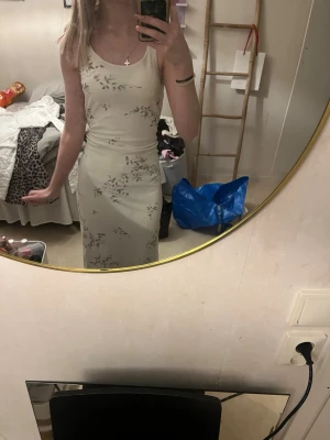 Ljusblommig balklänning  - Jätte fin balklänning i vit med blommor i gröna och guldiga detaljer. Skulle gissa på storlek S eller M (taggarna är tyvärr borta) 