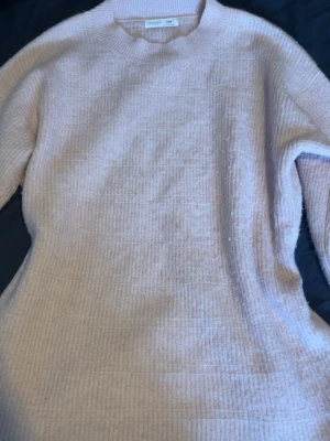 Ljusrosa stickad tröja från Object - Mysig ljusrosa stickad tröja från prime mark med rund halsringning och ribbade muddar. Tröjan har en avslappnad passform och är tillverkad i ett mjukt, strukturerat material som känns skönt mot huden. Perfekt för lager på lager under kyliga dagar.