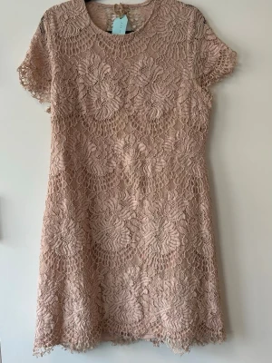 Beige spetsklänning med blommönster - Kort beige kl sturdy dig klänningsing från Y.A.S med vackert blommigt spetsmönster. Klänningen har rund halsringning sop korta ärmar och en sop öproppen rygg. Perfekt för sommarens alla tillfällen! Storlek XL men passar L. 