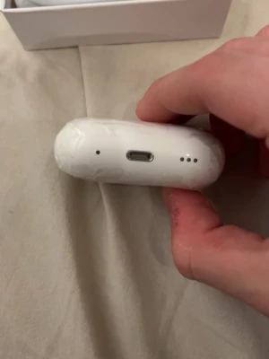 Vita trådlösa hörlurar med laddningsetui - Säljer ett par vita trådlösa in-ear hörlurar med tillhörande laddningsetui. Etuiet är ovalt och har USB-C laddningsport samt indikatorlampor. Smidig och stilren design i blank plast, perfekt för musik och samtal på språng.