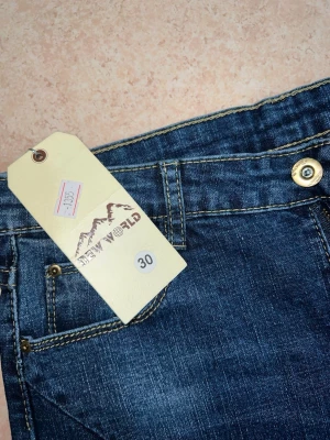 Mörkblå jeans med nitar - Snygga blå jeans med slitningar och pärldetaljer. Väldigt trendiga och ger en cool look. Aldrig använda, helt nya med lapp kvar. Stretchigt material och sitter fint på kroppen.